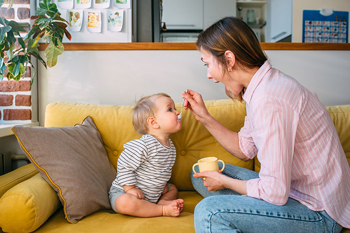 Mutter fuettert Kind leckerer Zwischenmahlzeit