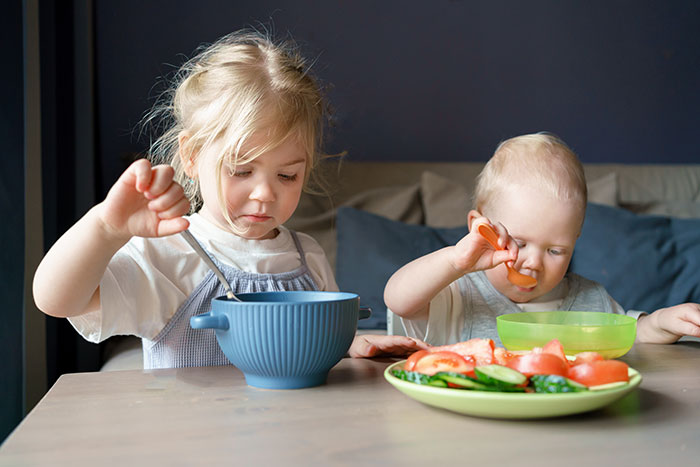 Kind und Kleinkind essen Salat und Mittagessen