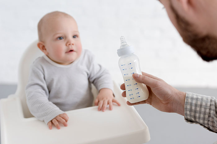 Kind wird vom Vater mit der Flasche gefüttert