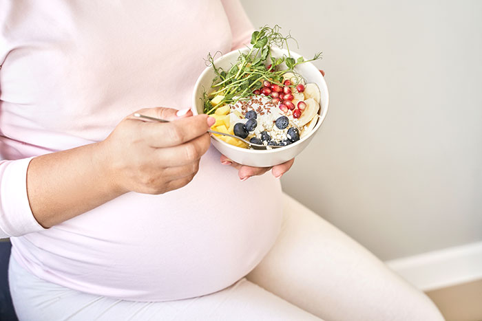 Schwangere Frau isst gesunde Fruchtbowl