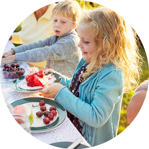 Kinder sitzen zusammen und essen Obst und Kuchen