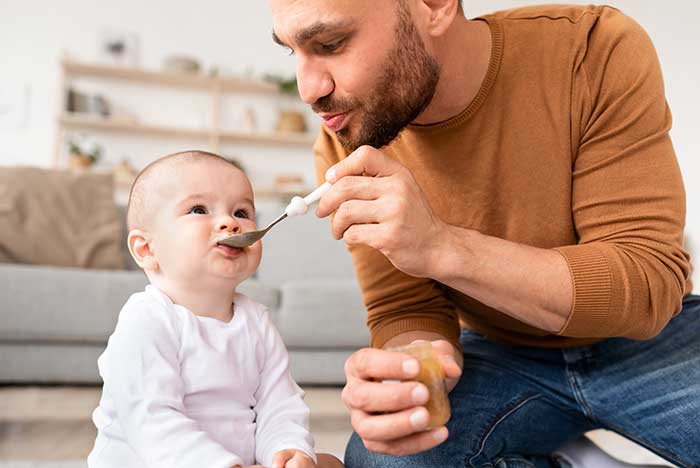 Vater fuettert Kind mit Brei